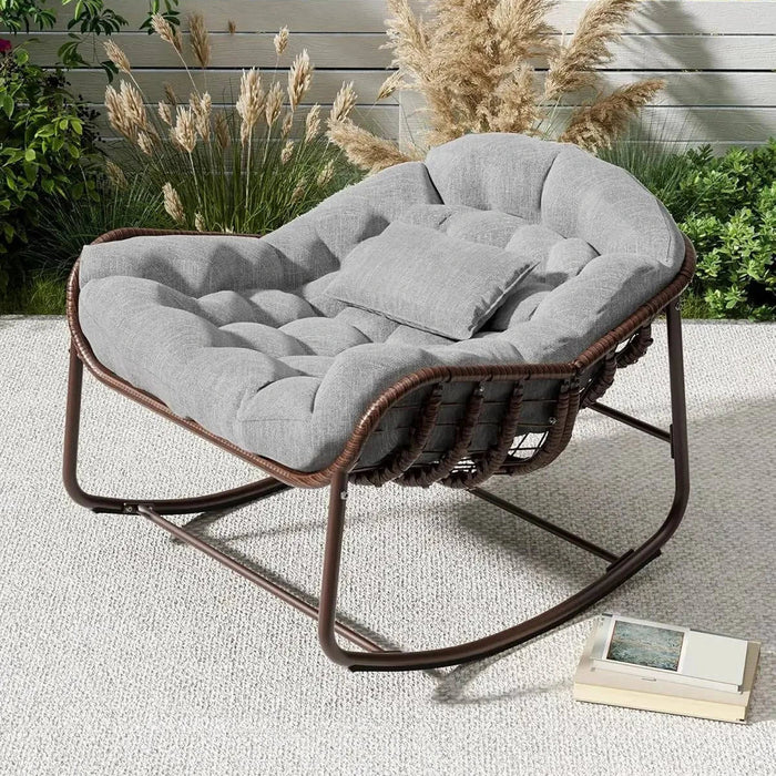 Fauteuil à bascule cocon en rotin gris, design confortable et moderne pour séjour ou espace détente.